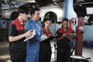 spécialiste conférence. Masculin superviseur ingénieur décris automobile suspension fixation avec mécanicien ouvrier Personnel équipes pour réparation travail à voiture un service garage et entretien emplois dans voiture industrie. photo