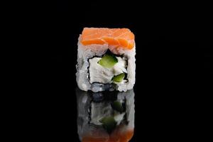 rouleau de sushi de philadelphie sur fond noir avec réflexion. rouleaux d'uramaki. photo