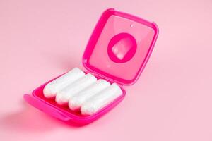 tampons dans une boîte rose. produits d'hygiène féminine sur fond pastel. photo