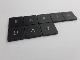le mot Terre journée orthographié en dehors avec noir boutons sur une blanc Contexte photo