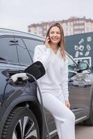 Jeune femme en utilisant une téléphone intelligent à Payer pour électrique voiture à le mise en charge gare. recharger batterie de mise en charge gare. photo