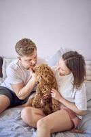 Jeune couple est en portant une cockapoo chien dans leur bras sur le lit photo