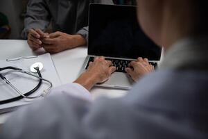 soins de santé fournisseur travail sur soins de santé Les données dans une médical enregistrements système sur une portable avec médical les documents et une stéthoscope sur le tableau. photo