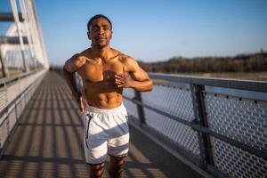 Jeune Afro-américain homme est le jogging sur le pont dans le ville. photo