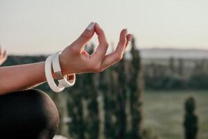 aptitude femme. bien à la recherche milieu vieilli femme avec longue cheveux, aptitude instructeur dans leggings et hauts Faire élongation et pilates sur le Roche près forêt. femelle aptitude yoga routine concept. photo