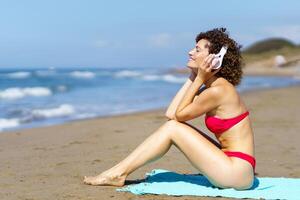 content femme écoute à la musique sur sablonneux plage photo