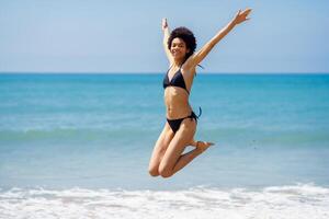 actif femme dans bikini sauter près mer photo