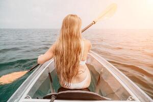 femme dans kayak retour voir. content Jeune femme avec longue cheveux flottant dans transparent kayak sur le cristal clair mer. été vacances vacances et de bonne humeur femelle gens relaxant ayant amusement sur le bateau photo