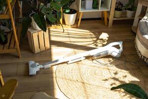 une femme aspirateurs une rond tapis dans une maison parmi maison les plantes avec une main vide nettoyeur. général nettoyage de le loger, nettoyage un service et femme au foyer photo