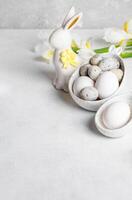 verticale Pâques carte. des œufs dans figuré boules, céramique lapin, blanc Jaune iris fleurs. copie espace. photo
