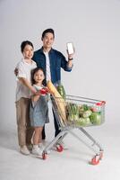 image de asiatique famille pousser une supermarché Chariot tandis que achats, isolé sur blanc Contexte photo