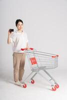 souriant femme Heureusement pousser une supermarché Chariot, isolé sur blanc Contexte photo