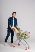 content souriant homme pousser supermarché Chariot isolé sur blanc Contexte photo
