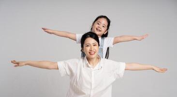 portrait de un asiatique mère et fille posant sur une blanc Contexte photo