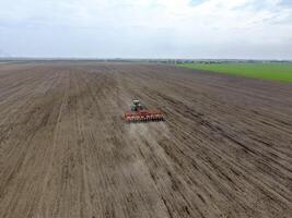 semis de maïs. tracteur avec une semoir sur le champ. en utilisant une semoir pour plantation maïs. photo