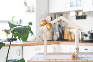 clé et minuscule maison de confortable Accueil avec Pâques décor avec Couleur des œufs sur table de cuisine. bâtiment, conception, projet, en mouvement à Nouveau loger, hypothèque, assurance, location et achat réel biens photo