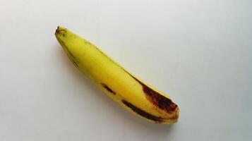 Jaune banane avec brunâtre noir taches sur une blanc Contexte photo