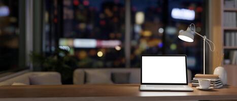 une portable maquette sur une en bois bureau dans une contemporain Accueil Bureau à nuit illuminé par faible lumières. photo