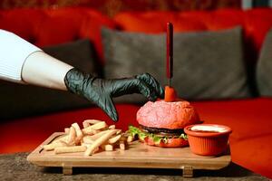 la personne dans noir gants appliquant ketchup à une Hamburger photo