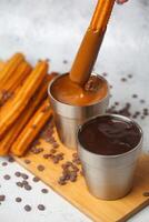 la personne plongement Churros dans une tasse de Chocolat photo