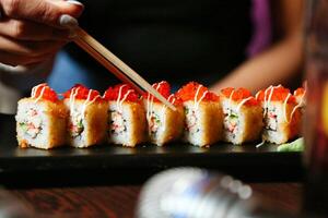 la personne en portant baguettes plus de une assiette de Sushi photo