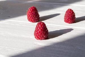 mûr framboises sur une blanc en bois Contexte. photo