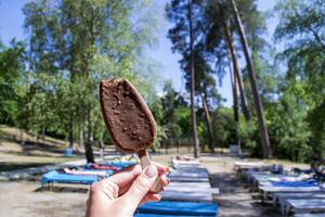 un la glace crème dans femelle bras contre une vert arbre Contexte. photo