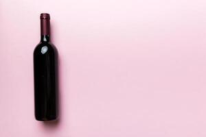 un bouteille de rouge du vin sur coloré tableau. plat poser, Haut vue avec copie espace photo