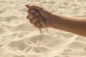 le le sable est verser de femme mains. photo