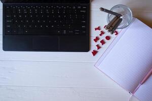 une tablette, carnet de notes, des crayons et multicolore des lettres sur une blanc en bois bureau. bureau Haut voir. photo