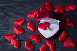 engagement bague dans une rouge boîte sur une l'amour cœurs Contexte. photo