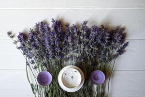 lavande fleurs, bougies et crème sur une blanc en bois Contexte. beauté se soucier. Haut voir. photo