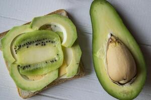 le des sandwichs avec Avocat et kiwi sur une blanc en bois Contexte. photo