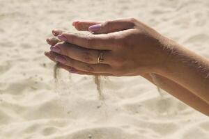 le le sable est verser de femme mains. photo