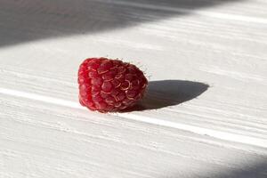 mûr framboises sur une blanc en bois Contexte. photo