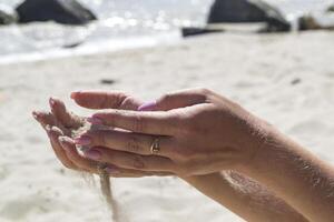 le le sable est verser de femme mains. photo