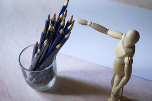 coloré des crayons, vide papier et mannequin pour dessin sur le tableau. photo