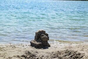 le des pierres sur le côte, contre une bleu l'eau Contexte. photo