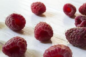 mûr framboises sur une blanc en bois Contexte. photo