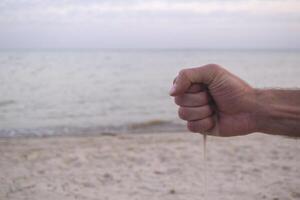 le le sable est verser de Masculin mains. photo