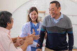 asiatique Jeune infirmière soutien Sénior plus âgée homme marcher avec marcheur. magnifique infirmière Aidez-moi et prendre se soucier. personnes âgées mature grand-père patient Faire physique thérapie avec une groupe de Sénior copains dans hôpital. photo