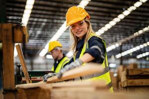 femme nettoyage Charpente bois dans foncé entrepôt industrie. équipe ouvrier Charpentier portant sécurité uniforme et difficile chapeau travail et vérification le qualité de en bois des produits à atelier fabrication. photo