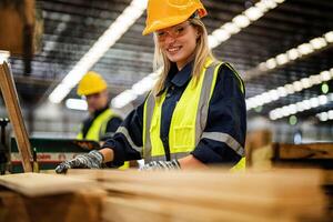 femme nettoyage Charpente bois dans foncé entrepôt industrie. équipe ouvrier Charpentier portant sécurité uniforme et difficile chapeau travail et vérification le qualité de en bois des produits à atelier fabrication. photo