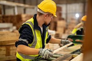 homme nettoyage Charpente bois dans foncé entrepôt industrie. équipe ouvrier Charpentier portant sécurité uniforme et difficile chapeau travail et vérification le qualité de en bois des produits à atelier fabrication. photo