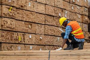 africain ouvriers homme ingénierie en marchant et inspecter avec travail suite robe et main gant dans Charpente bois entrepôt. concept de intelligent industrie ouvrier en fonctionnement. bois des usines produire bois palais. photo