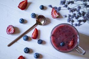 le fruit smoothie dans une verre tasse, et mûr des fruits sur le tableau. photo