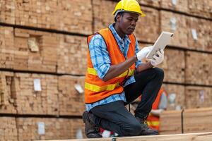 africain ouvriers homme ingénierie en marchant et inspecter avec travail suite robe et main gant dans Charpente bois entrepôt. concept de intelligent industrie ouvrier en fonctionnement. bois des usines produire bois palais. photo