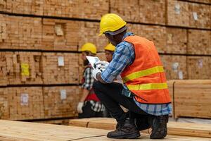 africain ouvriers homme ingénierie en marchant et inspecter avec travail suite robe et main gant dans Charpente bois entrepôt. concept de intelligent industrie ouvrier en fonctionnement. bois des usines produire bois palais. photo