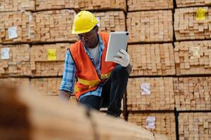 africain ouvriers homme ingénierie en marchant et inspecter avec travail suite robe et main gant dans Charpente bois entrepôt. concept de intelligent industrie ouvrier en fonctionnement. bois des usines produire bois palais. photo