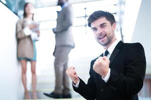 affaires gens et Bureau concept. content souriant homme d'affaire dans foncé costume. portrait de souriant milieu adulte homme d'affaire permanent à entreprise bureau. homme d'affaire souriant avec bras franchi dans bureau. photo